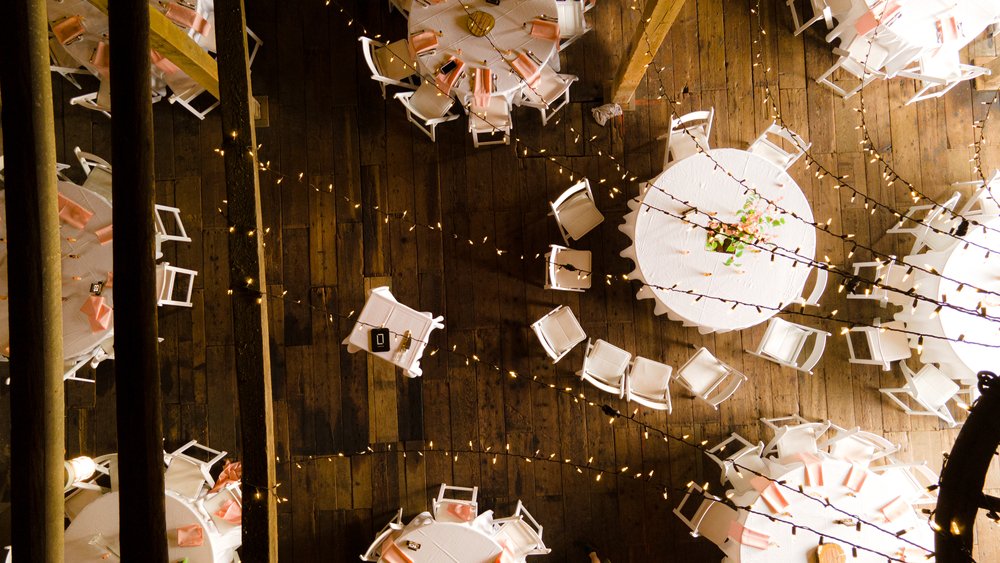 Round tables with white chairs, pink napkins and string lights